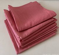 Stack of eight folded chrysanthemum pink linen napkins showing their color and texture.
