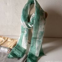 Green and white silk scarf draped on mannequin, showing coloration and design
