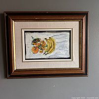 Full view of the framed original oil painting showing bananas and oranges on a white surface.