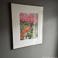 Framed watercolor painting showing spring flowers with pink and orange blossoms, green foliage, and clear and brown glass bottles, hung on wall.