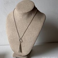 Front view of necklace on linen bust display showing chain and teardrop pendant hanging from oval loop.