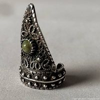 Side angle showing the ring's pointed and filigree decorated top with green agate inset.