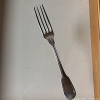 Photo of sterling silver serving fork, showing entire length and fork tines, highlighting condition and design details.