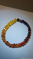 Photo showing full view of a polished bead Baltic amber bracelet with visible gradient from yellow to dark brown amber beads.