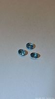 Three lagoon blue Cambodian zircon gemstones shown on a plain background. The stones are oval faceted, showing good clarity and brilliance.