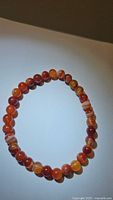 Full view of the natural red agate stretchy bracelet showing the round beads and natural color patterns.
