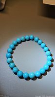 Clear photo of the natural turquoise bracelet showing round, polished 8mm beads in robin's egg blue, arranged in a circle on a flat surface.