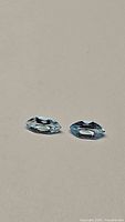 Pair of natural marquis cut sky blue topaz gemstones on neutral background. Gems show faceted cuts and light reflection.