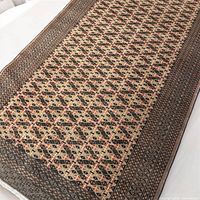 Close-up angle showing the detailed geometric pattern and border of the Turkmen rug.