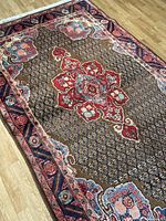 Full view of rug laid flat on wooden floor showing overall pattern and condition