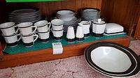 Full set of BKJ china arranged on shelf, showing cups, saucers, salt and pepper shakers, covered butter dish, cream and sugar set
