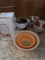 Lot showing all items including boxed floral coffee carafe, white fondue set with skewers, nested peach and cream Pyrex bowls, and glass chip and dip set with brown and gold leaf design.