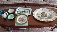 View of entire set of assorted dishware including turkey platter, plates, bowls, and cup on wooden table