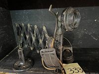 Front view of black candlestick telephone with earpiece attached and accordion style extendable wall mount bracket.