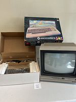 Overview of boxed Commodore 64 computer, accessories and video monitor