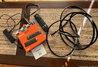 Fire TV Stick device, remote, USB power adapter, and HDMI cable on table with original box and lot card