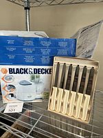 Boxed Black & Decker food processor with instruction manual and cardboard boxed set of 6 steak cutting knives with white handles.
