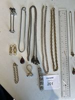 Full lot laid out including chains, earrings, pendants, bracelet and cufflinks with ruler for scale