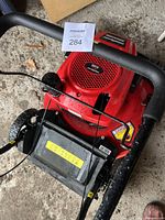 Top view showing red engine cover with ventilation, black handlebar with control cables, and part of the wheeled base.