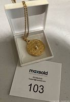 Gold filled floral locket necklace displayed inside a white jewelry box, showing front side with pearl accent.