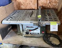 Full side view of Makita 2703 benchtop table saw showing metal work surface, blade slot, cam locking rip fence, and power cord.