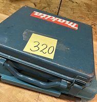 Closed teal metal Makita case with handle and sticker marked '320'