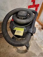Top angle of Shop-Vac showing hose coiled on top and wheels.