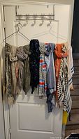 Scarves hanging on a door rack showing various colors and patterns including beige, gray, navy blue, orange, white, and stripes.