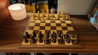 Chessboard set up and pieces arranged on the board showing natural wood pieces facing camera.