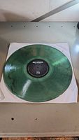 Photo of the green translucent vinyl record by Big Wreck titled 'Bag of Tricks' laid on a white sleeve on a table.