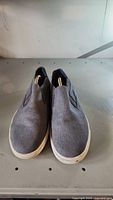 Front view of the men's UGG shoes in grey fabric, slip-on style showing some usage wear