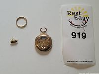 All three items displayed: pocket watch, ring, and earring stud