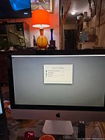 Wide view of iMac on desk showing front of silver aluminum all-in-one unit and stand