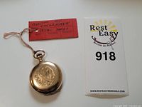 Front view of pocket watch on lot tag and auction card