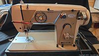 Front view of beige Omega sewing machine showing dial, needle area, and control panel