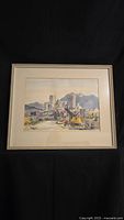 Framed watercolor painting showing a full view of the cityscape with mountains and excavator.