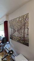 Photo of the entire painting mounted on a white wall above exercise equipment, showing the tree-lined path artwork.