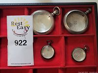 Four sterling silver pocket watch cases on red tray