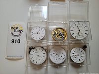 Six vintage watch movements in plastic containers; mixed watch dials and exposed gears