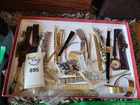 Wide shot of all wrist watch faces and bands in a box, showing variety of metal and leather bands and watch faces