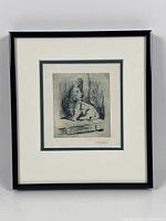 Framed etching featuring a dog, signed by artist F.E. Jeffery, shown in its frame with white matting and black frame.