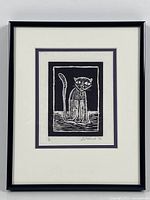 Framed woodcut print of a cat stylized in black and white.