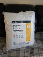 Photo of packaging showing Anko brand, All Seasons Quilt size 173cm x 218cm, cotton cover, medium warmth, easy care icons and text.
