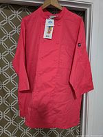 Front view of red chef jacket hanging, showing double-breasted button front and long sleeves.