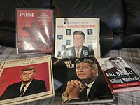 Photo showing the 2 vinyl records featuring JFK, 2 hardcover books about JFK, and one magazine in protective storage.