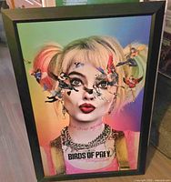 Front view of the framed colorful artwork featuring Harley Quinn from DC Comics Birds of Prey with multiple small flying characters around her head and a smooth black frame.