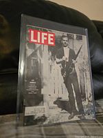 Front cover of LIFE magazine featuring Lee Harvey Oswald with rifle, protected in plastic sleeve, showing overall condition.