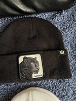 Black knit toque with embroidered panther patch on the cuff and small Goorin Bros. logo tag.