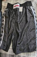 Full view of the black TOP TEN boxing shorts showing their length and elastic waistband with logo.