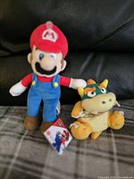 Photo of Mario and Bowser Nintendo plush toys displayed on a black surface.